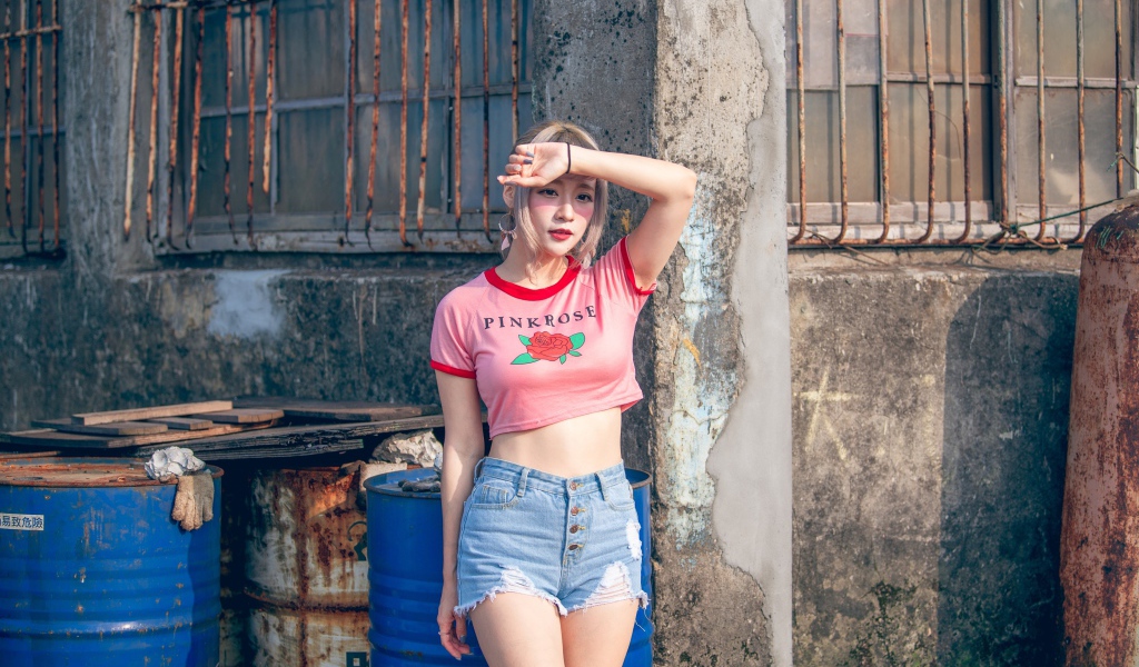 Молодая азиатка стоит у стены 