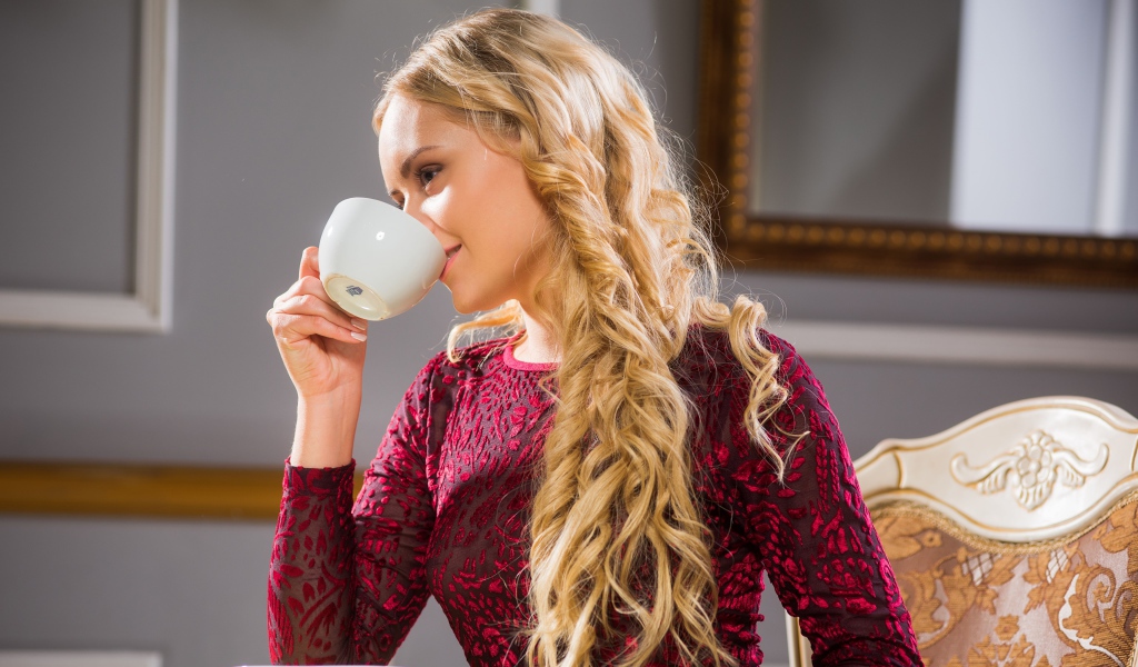 Молодая красивая девушка пьет кофе из белой чашки 