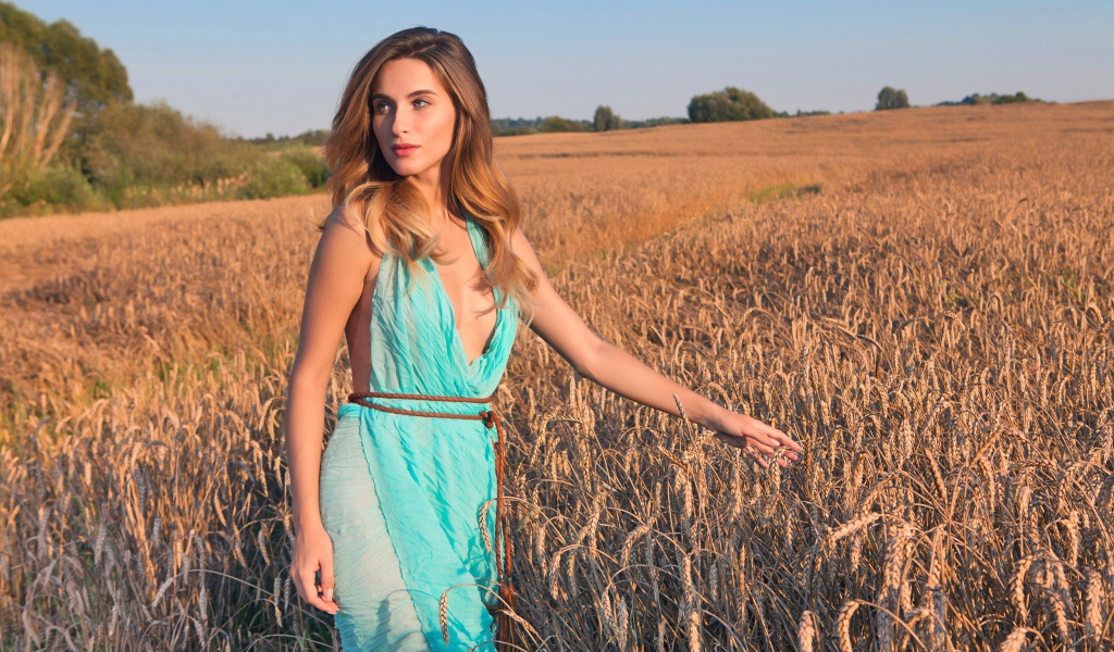 Молодая девушка в голубом платье на поле с пшеницей 