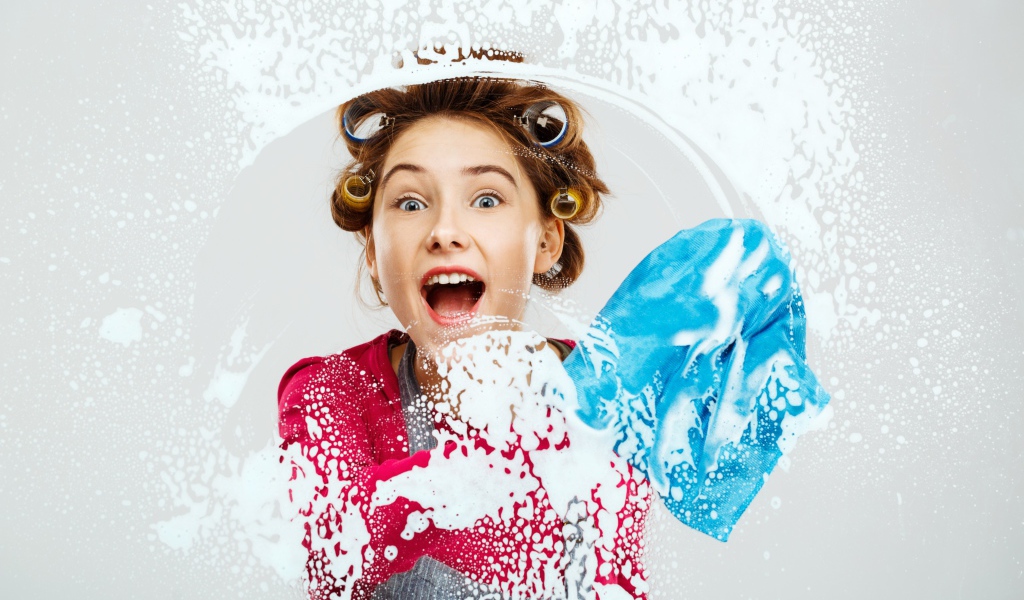 Молодая девушка в бигудях моет окно