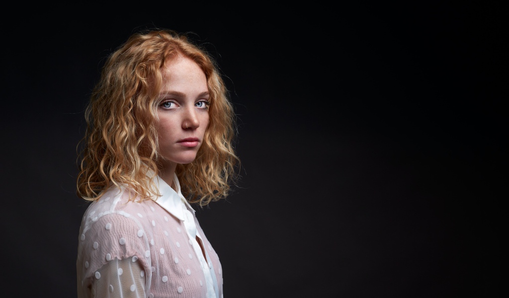 Молодая рыжеволосая девушка на черном фоне