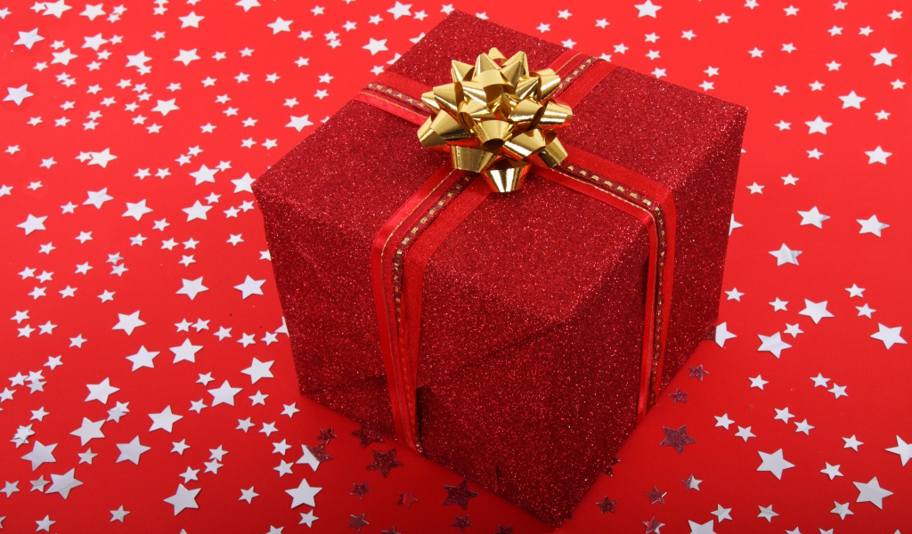 Большой подарок с бантом на красном фоне со звездами 