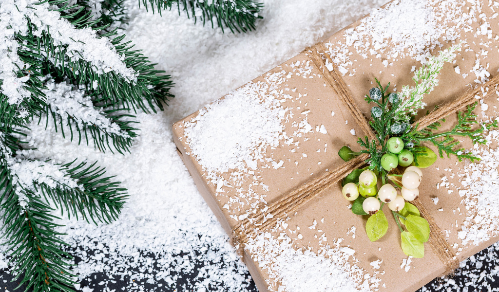 Подарок с заснеженной веткой ели на столе