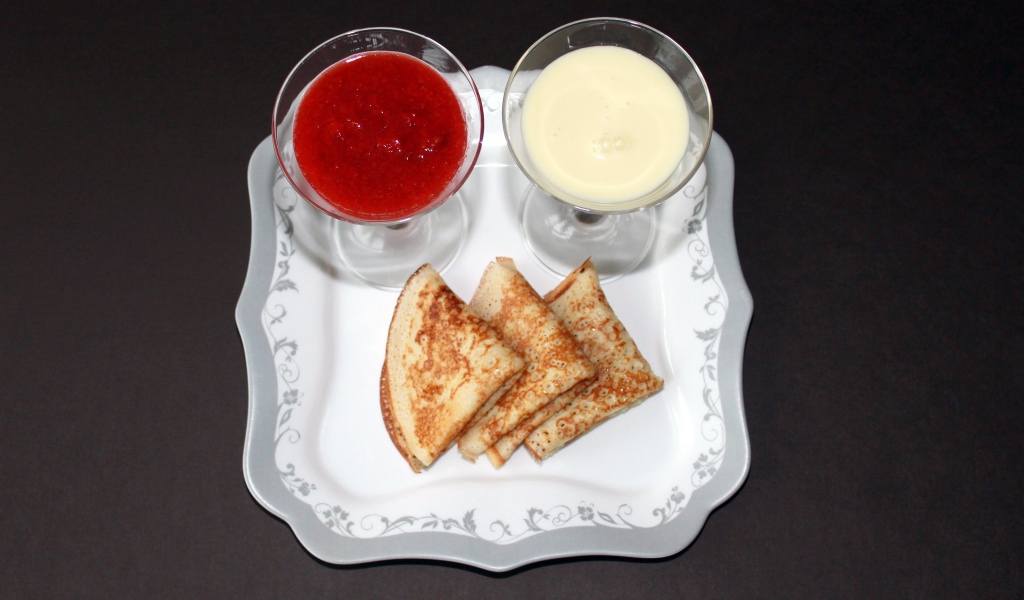 Блинчики с вареньем и сметаной на столе на Масленицу