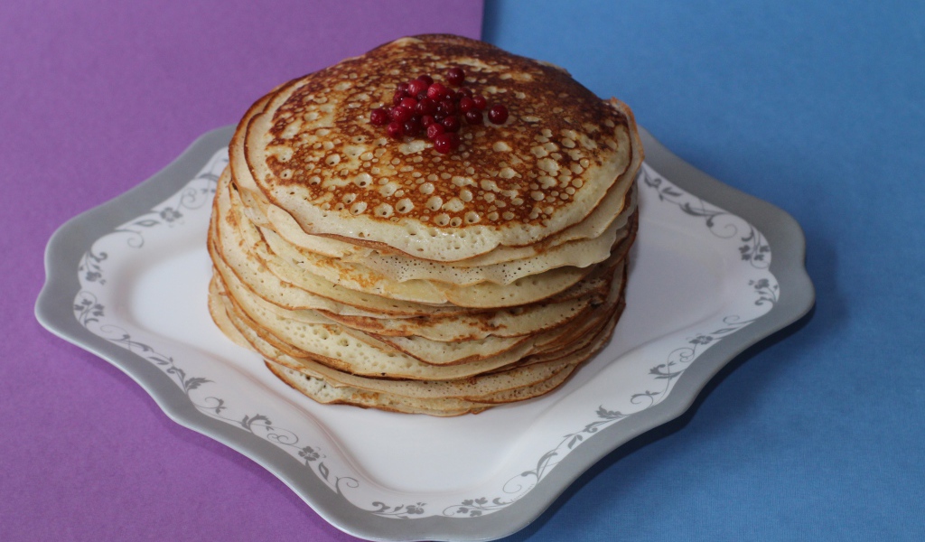 Румяные блины с ягодами на столе на Масленицу