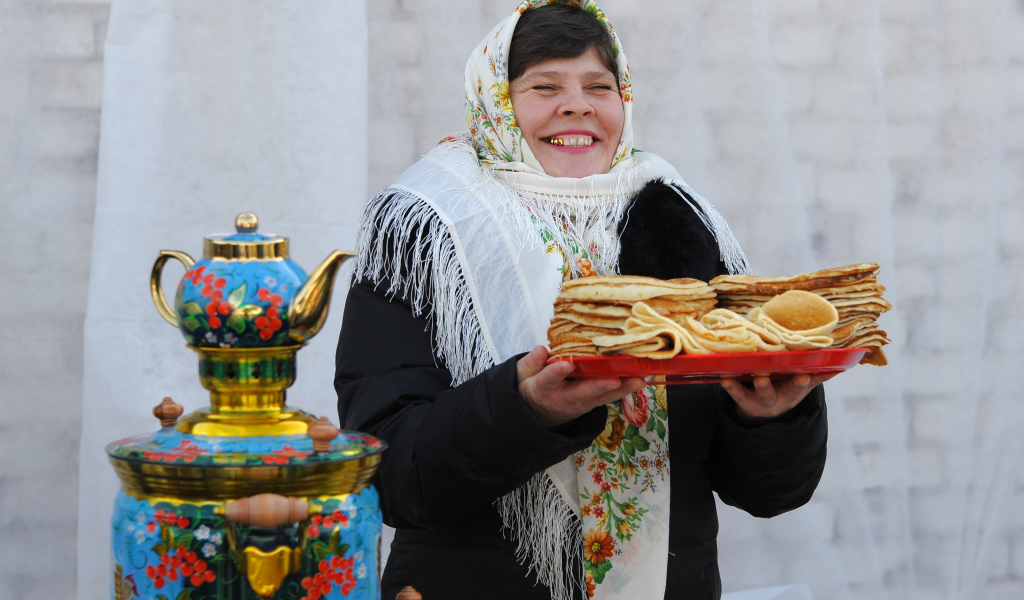 Женщина с блинами и самоваром на Масленицу