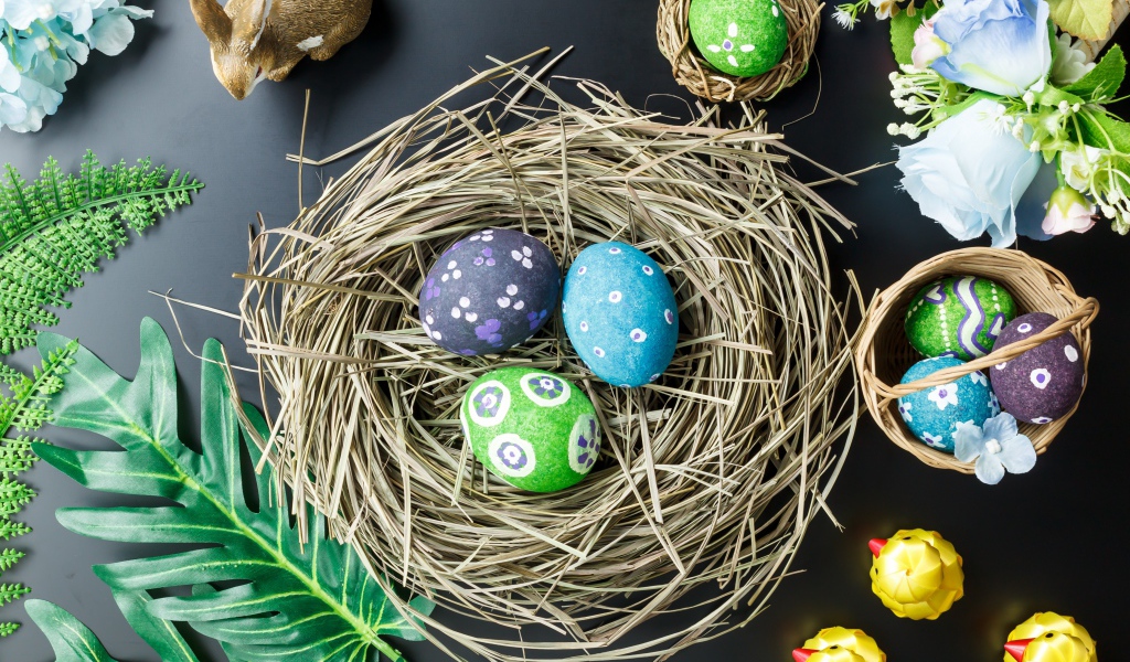 Яркие пасхальные яйца на столе в гнезде