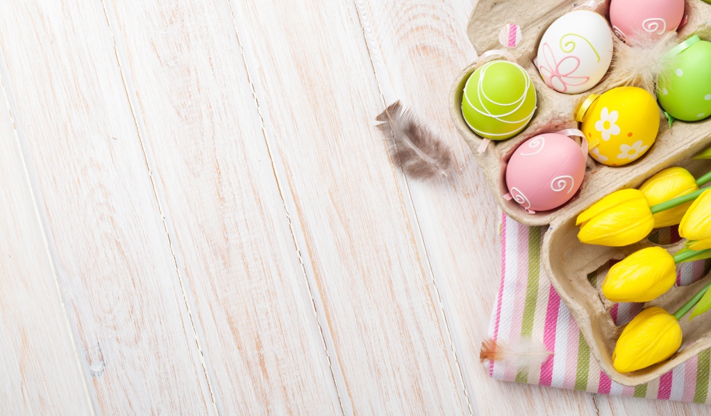 Крашеные пасхальные яйца на столе с тюльпанами