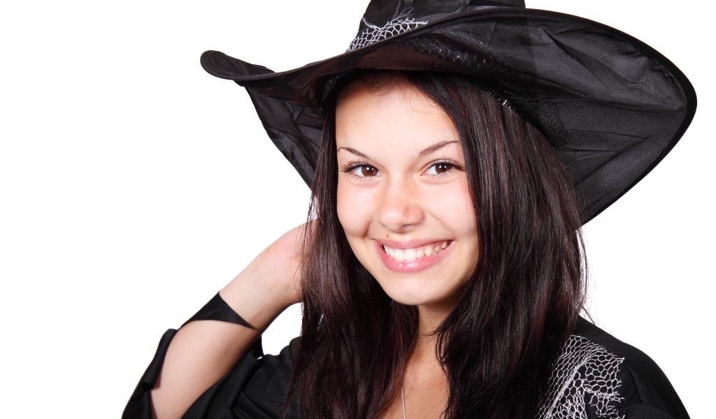 Улыбающаяся девушка в костюме ведьмы на Хэллоуин