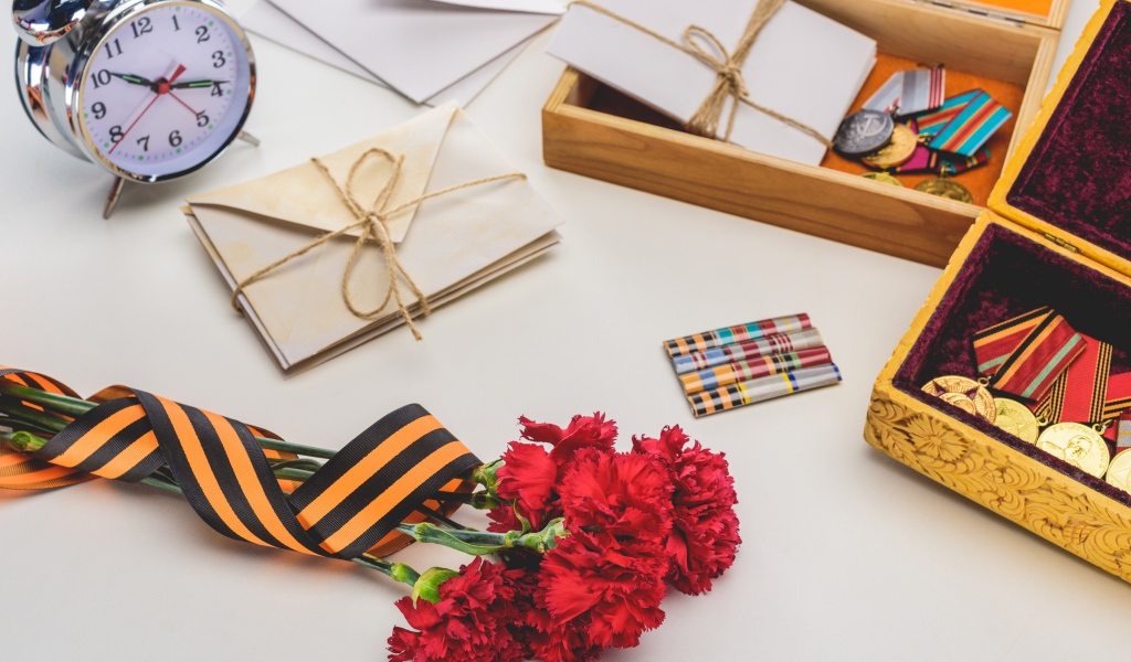 Букет красных гвоздик, ордена и часы на День победы 9 мая