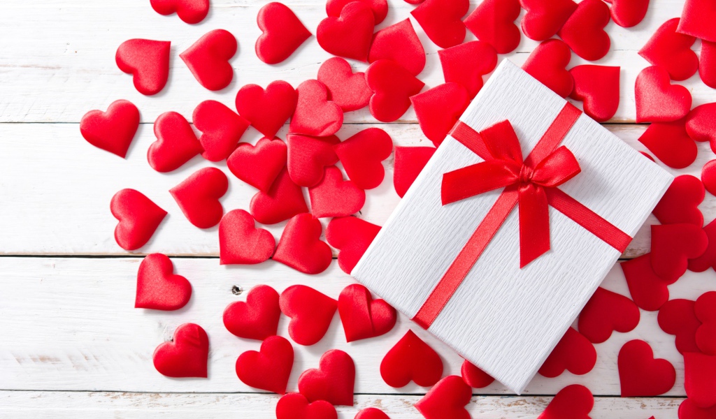 Подарок и много красных сердечек на белом фоне на День Святого Валентина
