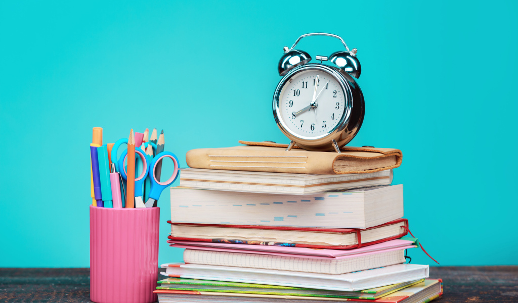 Будильник, книги и канцелярские предметы для школы