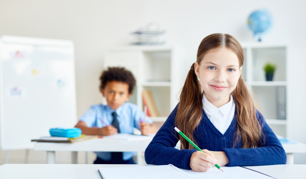 Девочка школьница сидит за партой в школе 