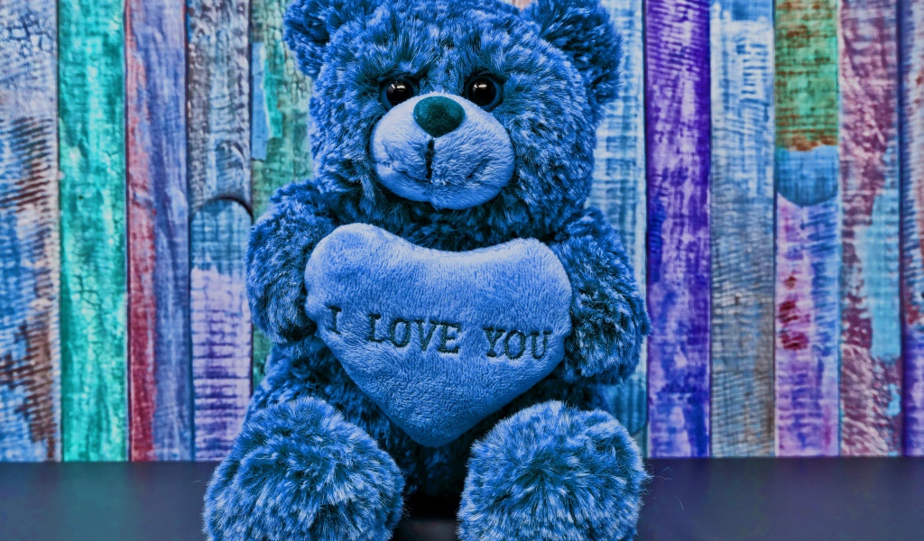 Синий медведь с сердцем на фоне забора