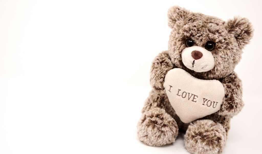 Меховая игрушка медвежонок с сердцем на белом фоне