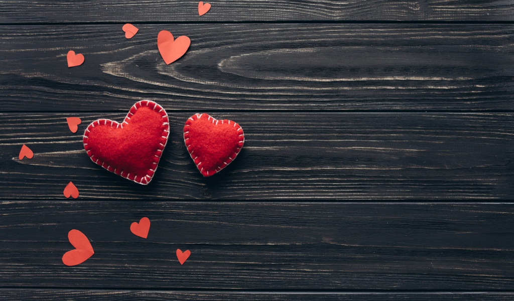 Два больших  красных сердца с маленькими  на деревянном столе 