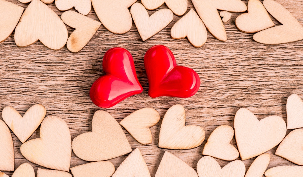 Два красных сердца и деревянные сердечки на столе