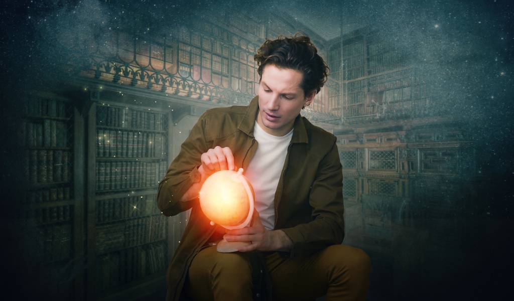 Мужчина в старой библиотеке со светящимся глобусом в руке 
