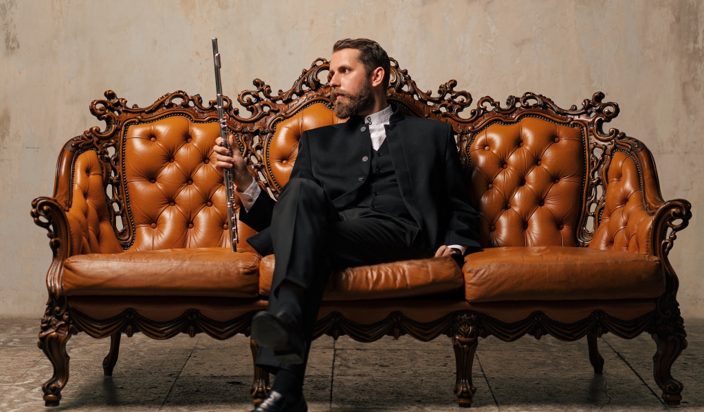 Солидный мужчина в костюме сидит на диване