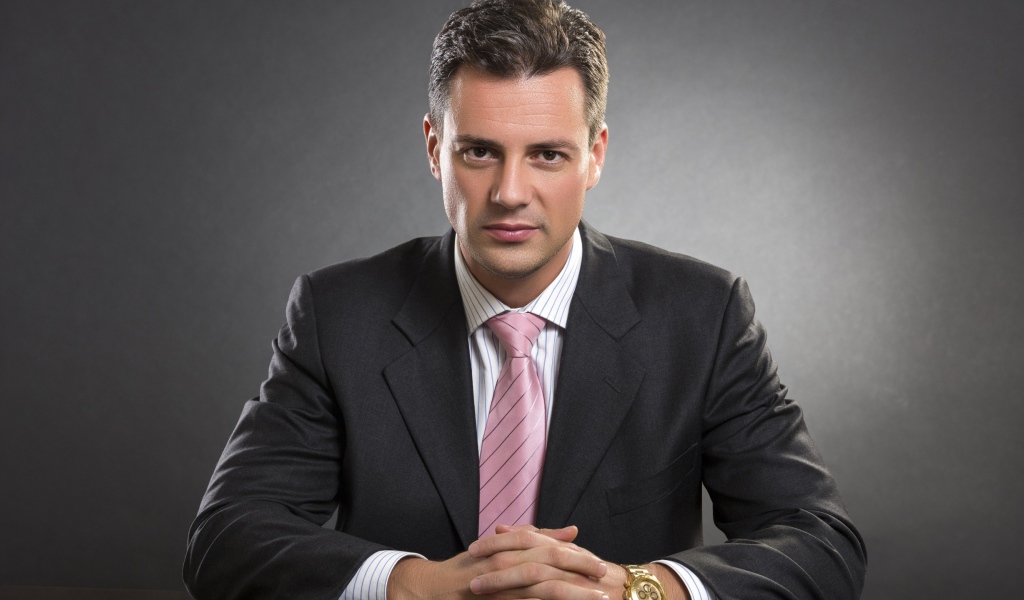 Деловой мужчина в костюме на фоне серой стены 