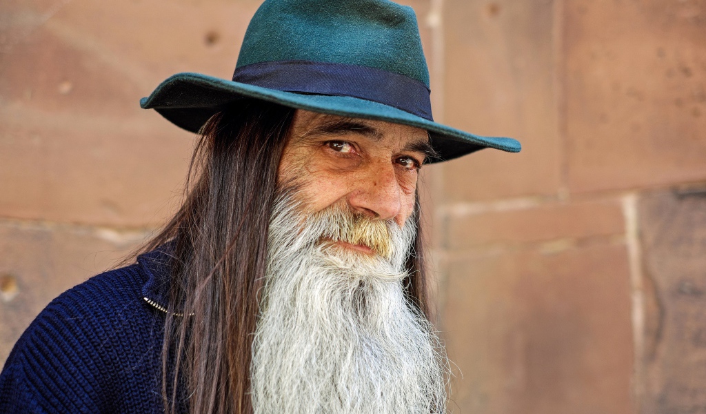 Пожилой мужчина с длинными волосами в шляпе 