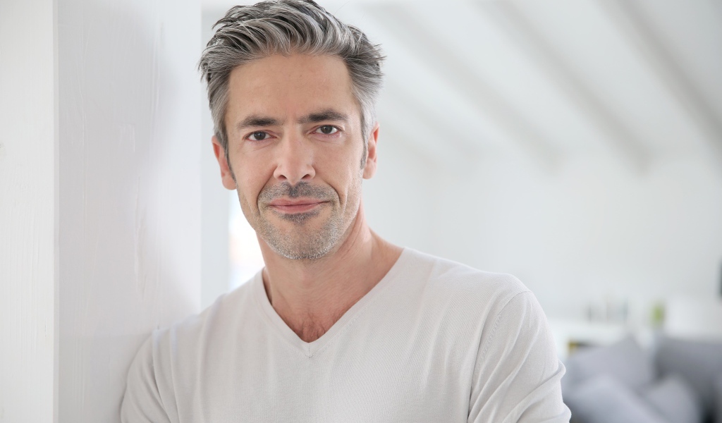 Седой стильный мужчина у стены