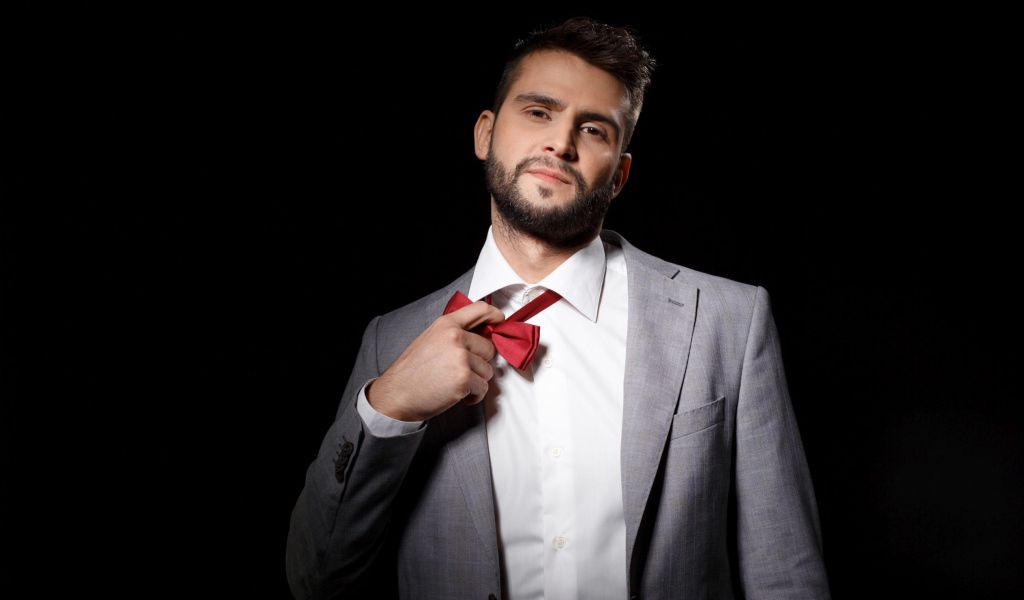 Красивый мужчина в сером пиджаке на черном фоне