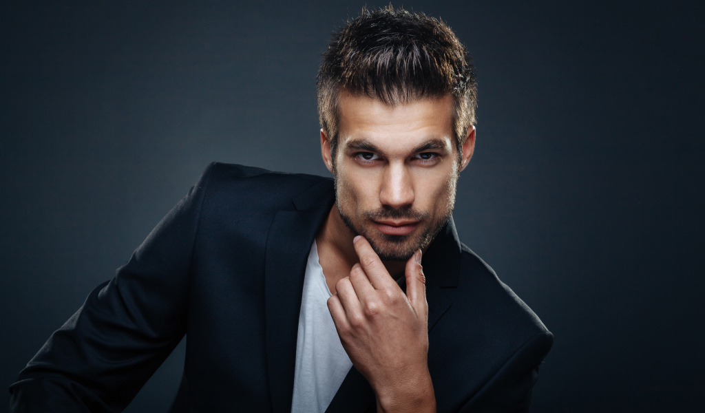 Красивый стильный мужчина в пиджаке на сером фоне 