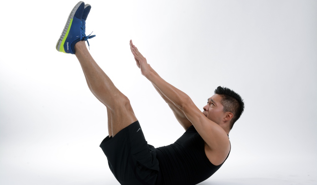 Мужчина спортсмен качает пресс на белом фоне