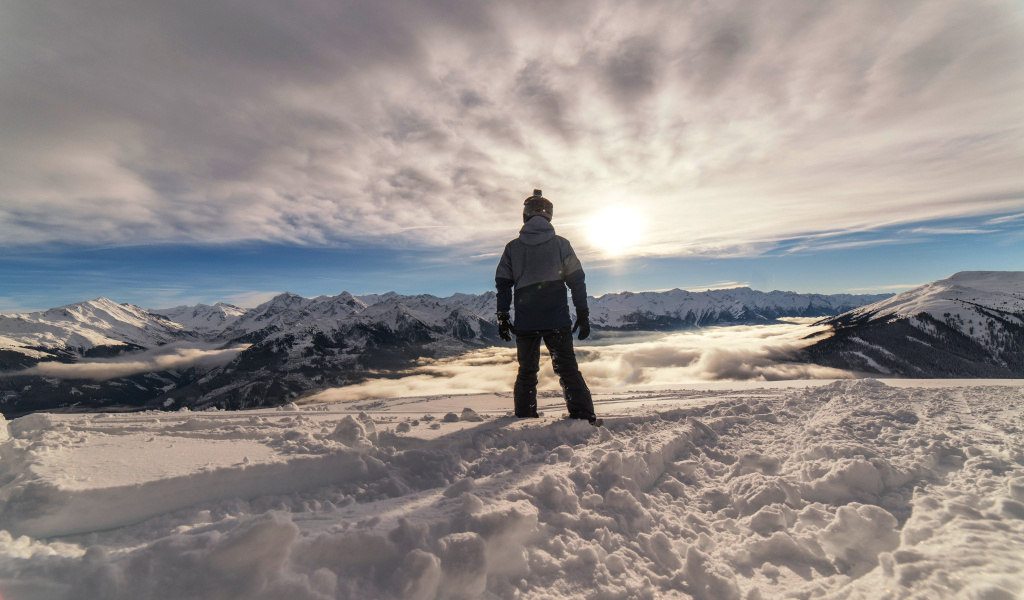 Человек в заснеженных горах в лучах солнца