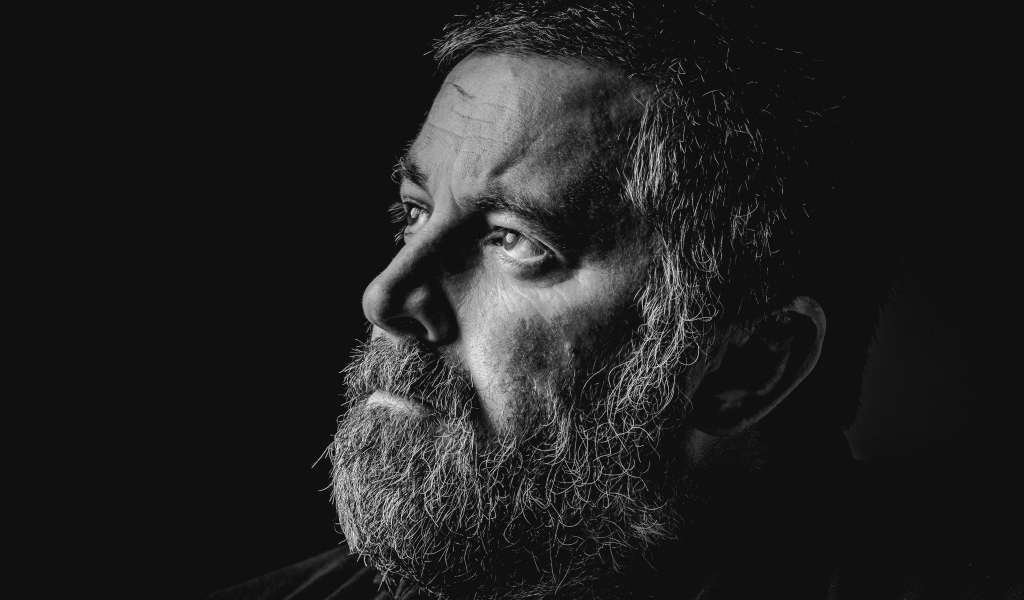 Мужчина с седой бородой на черном фоне 