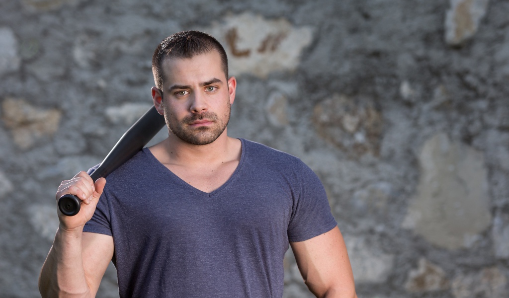 Серьезный парень с бейсбольной битой в руке 