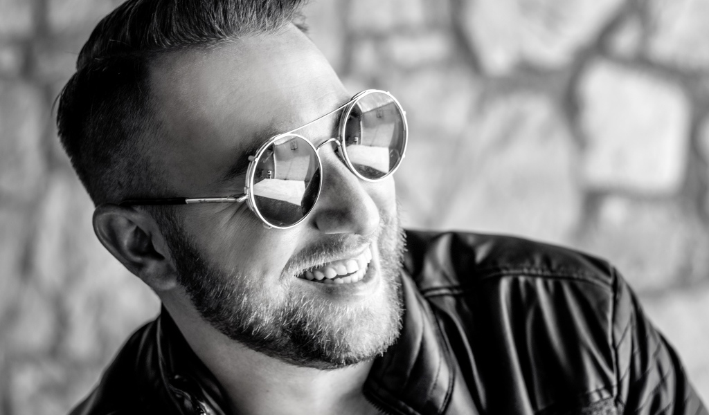 Улыбающийся брутальный мужчина в черных очках