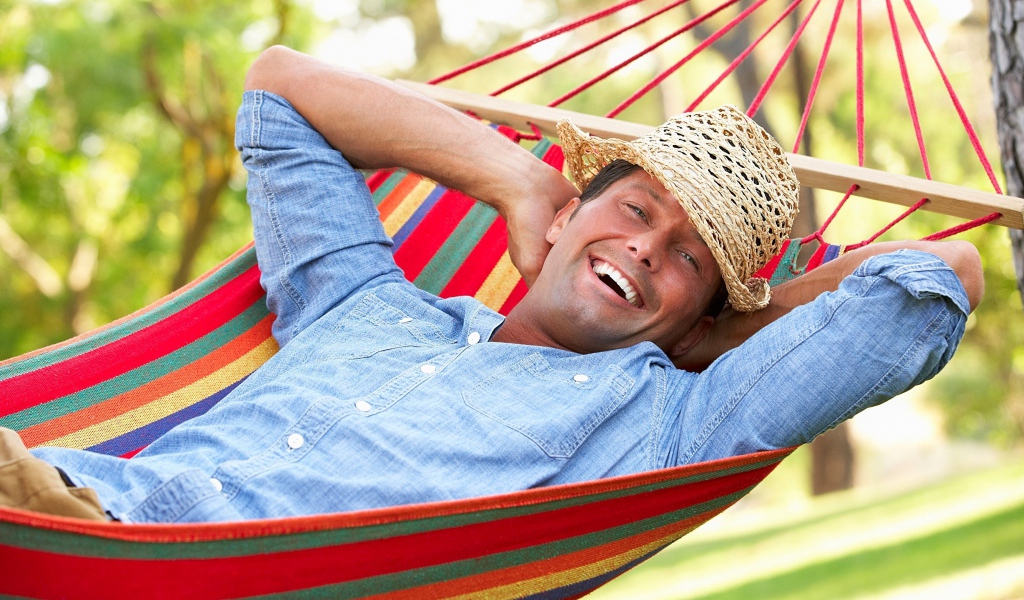 Улыбающийся мужчина спит в гамаке