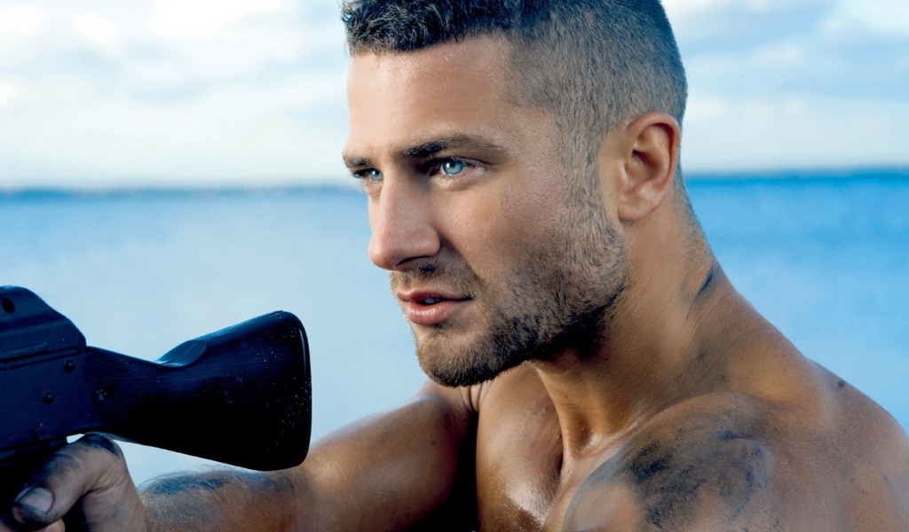 Сильный голубоглазый мужчина с винтовкой в руках 