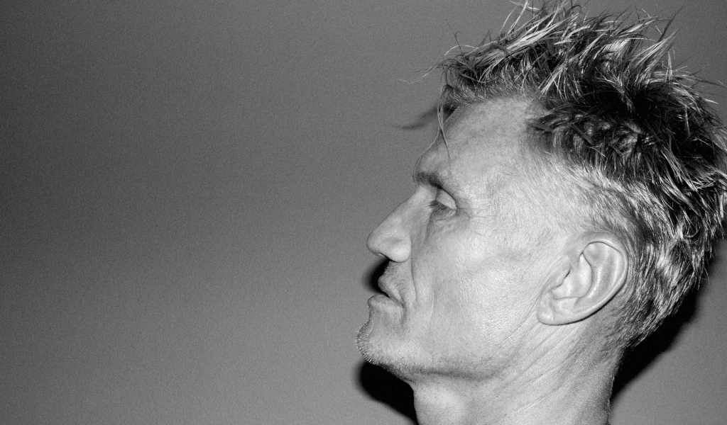 Лицо актера Дольфа Лундгрена боком на сером фоне