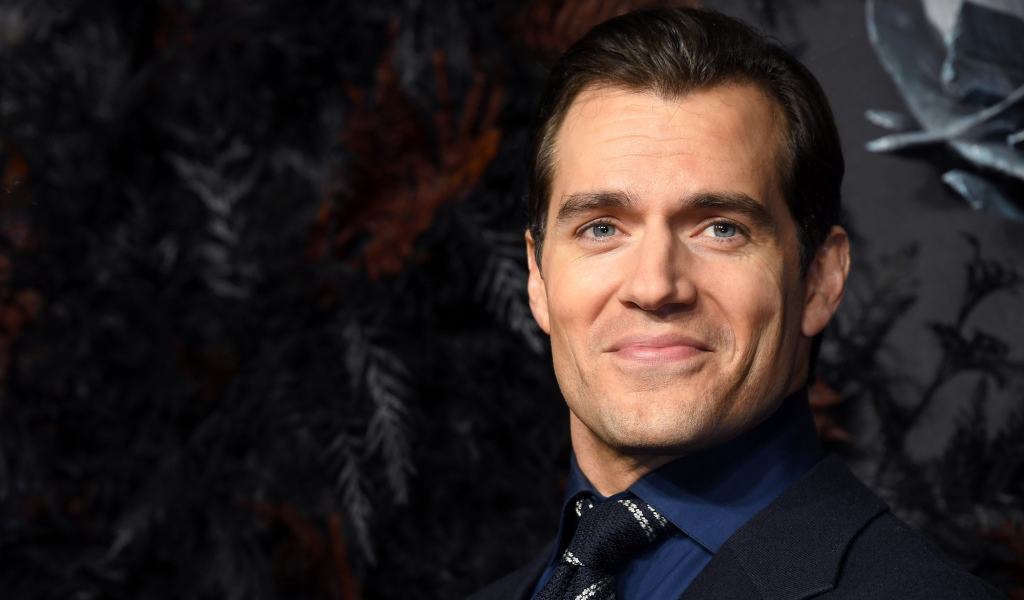 Улыбающийся актер Генри Кавилл в костюме