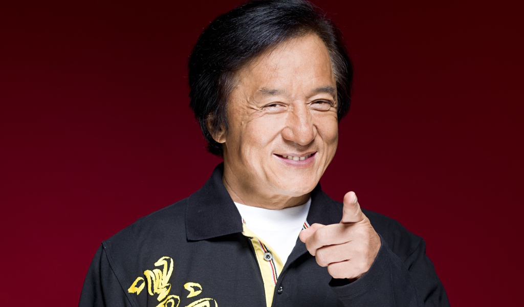 Улыбающийся мужчина, актер Джеки Чан на красном фоне