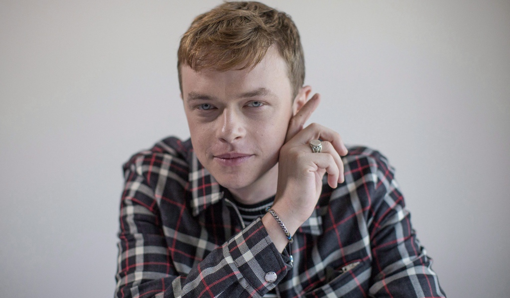 Молодой актер Дэйн Дехаан в рубашке на сером фоне