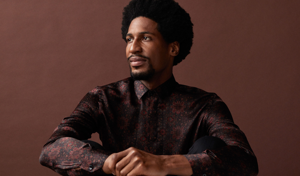 Музыкант Джонатан Батисте на коричневом фоне