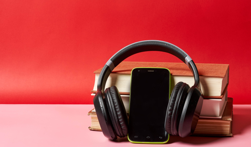 Смартфон, наушники и книги на красном фоне