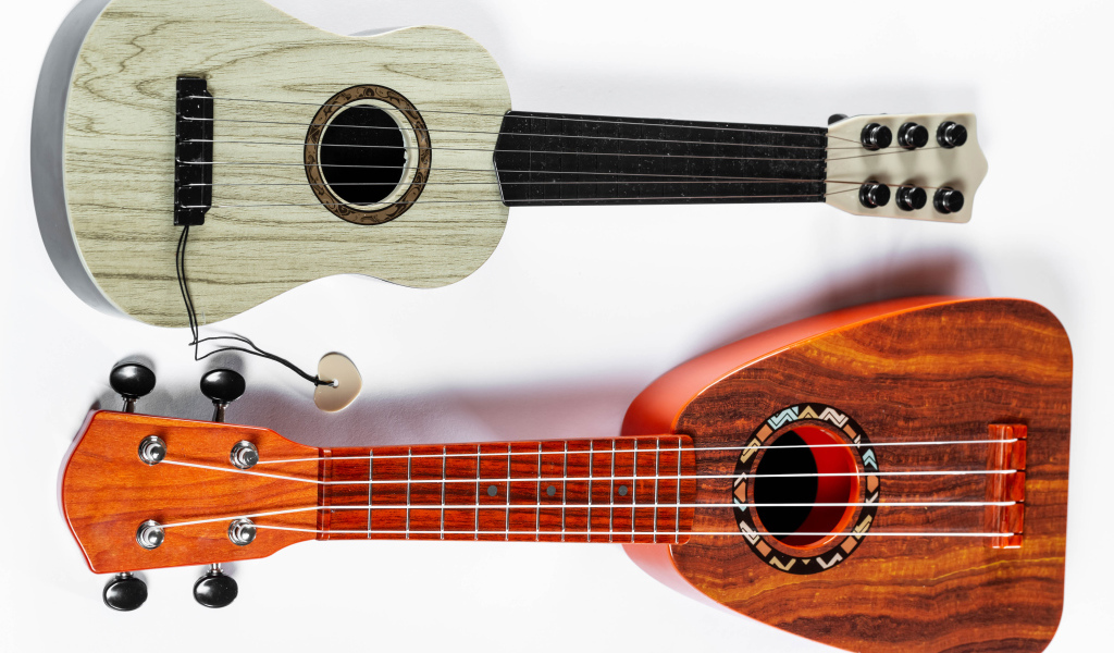 Две маленькие гитары укулеле на белом фоне