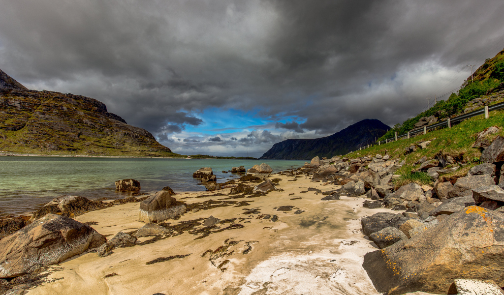 Большие камни на берегу фьорда под грозовым небом 