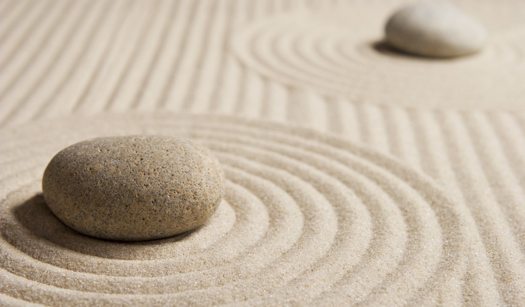 Большой серый камень на песке с кругами 
