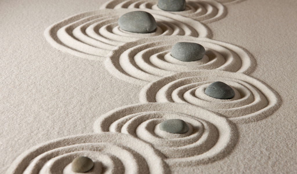 Маленькие серые камни с кругами на песке 
