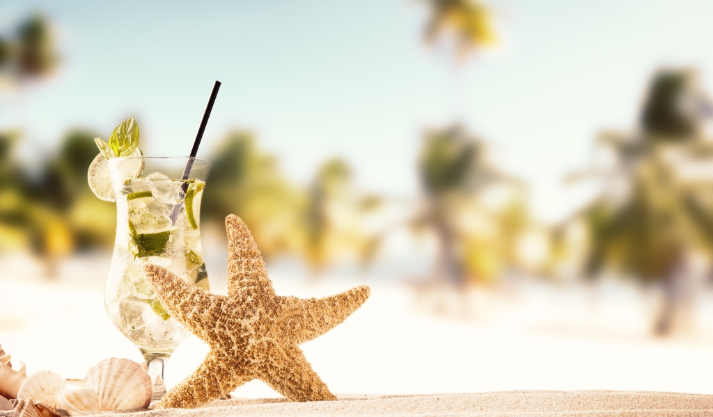 Морская звезда и бокал мохито на песке летом