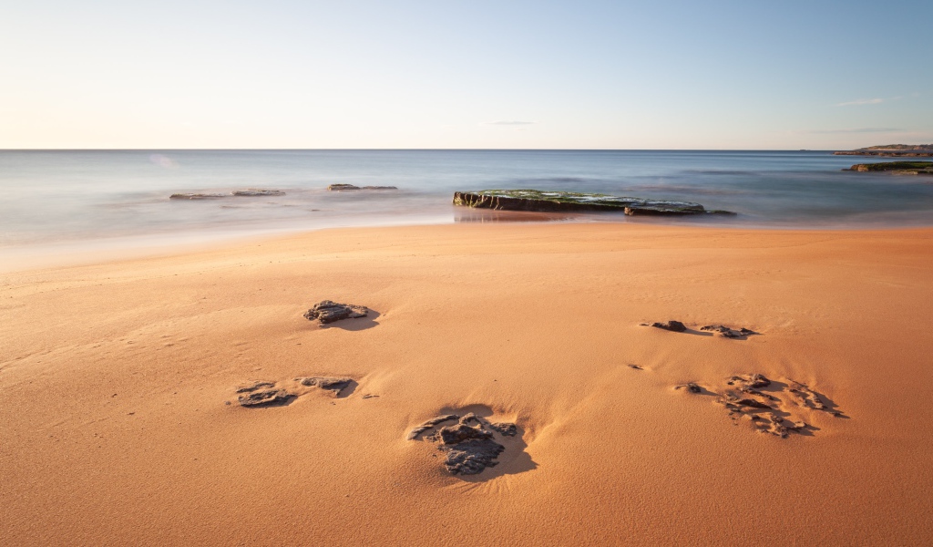 Камни в песке на берегу моря 