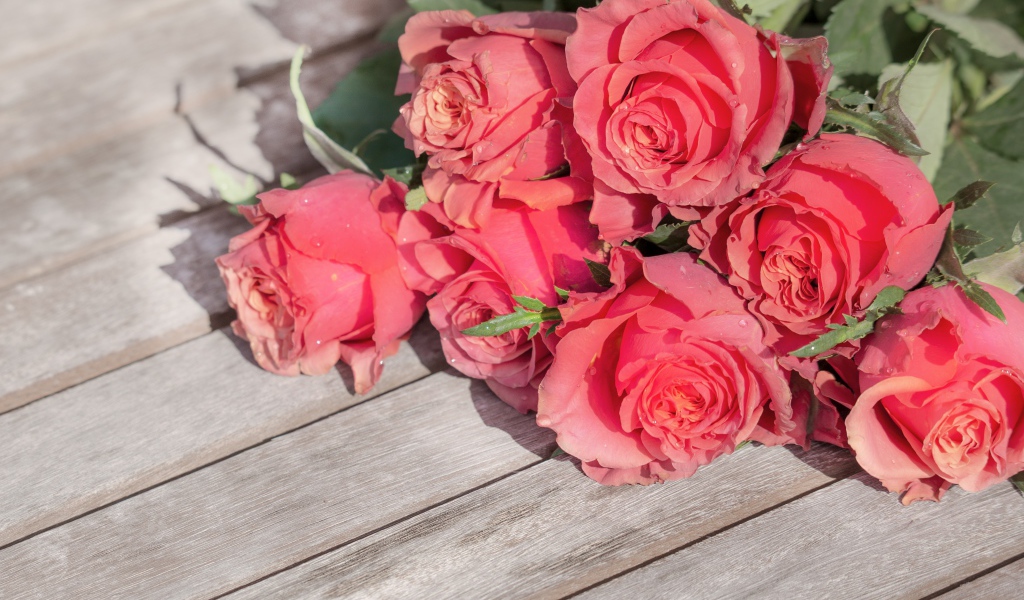 Букет розовых роз лежит на деревянном столе