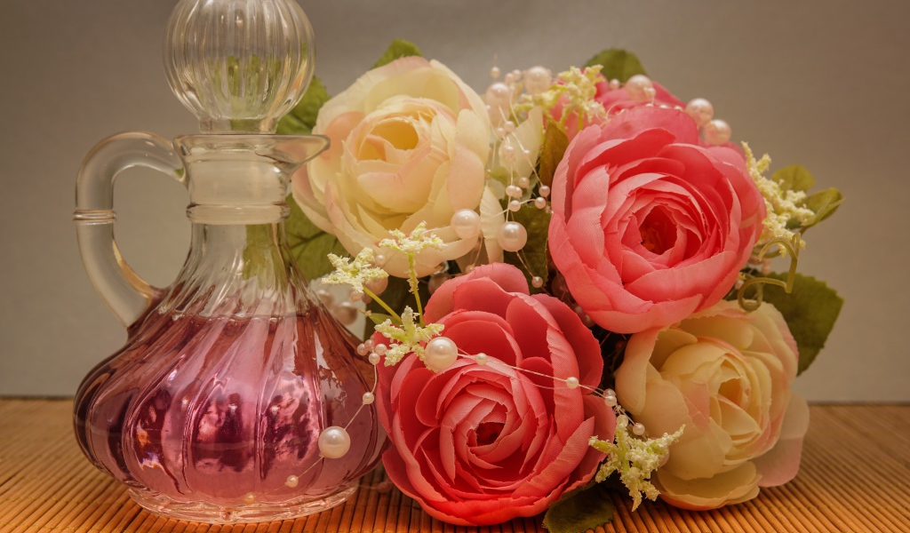 Красивый букет искусственных роз на столе с духами