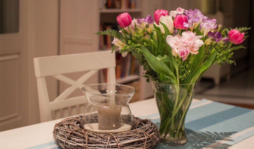 Красивый букет ярких цветов на столе со свечой